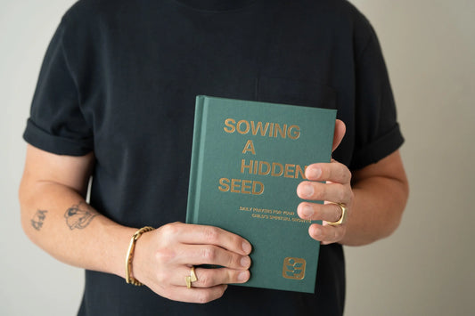 Sowing a Hidden Seed linen hardcover devotional held in hand